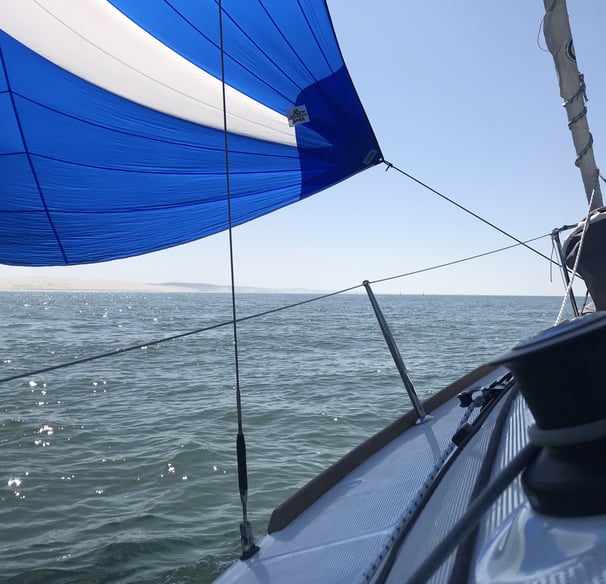 a sailboat sails through the water with a blue sky