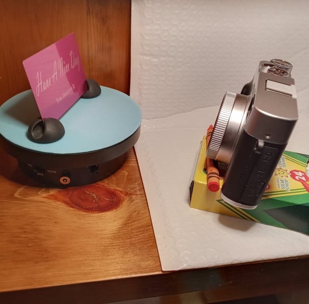 Using dollar store crayons as a tripod to take a photo of the metal card