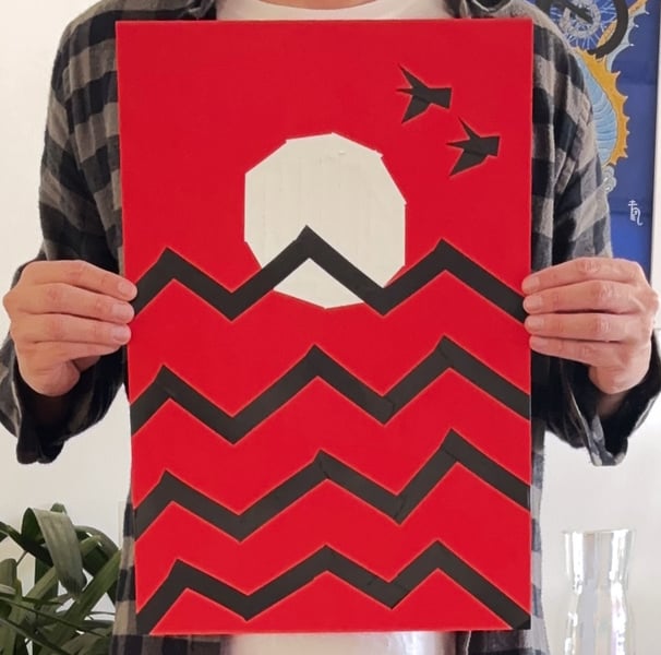 papel vermelho, onde um sol branco está desenhado com fitas, que também fazem o desenho de ondas pretas e duas aves no céu.