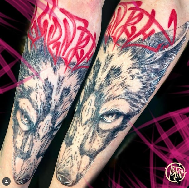 Tatouage réaliste de loup sur avant-bras avec lettrage rouge, réalisé par Datcha Tatouage à Gap 05