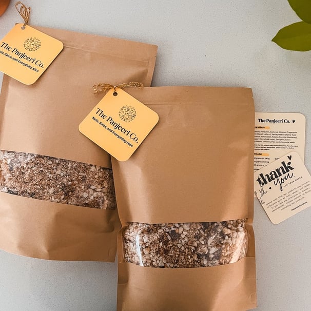 Two sealed, recyclable brown paper bags filled with handcrafted subcontinental granola (Panjeeri).