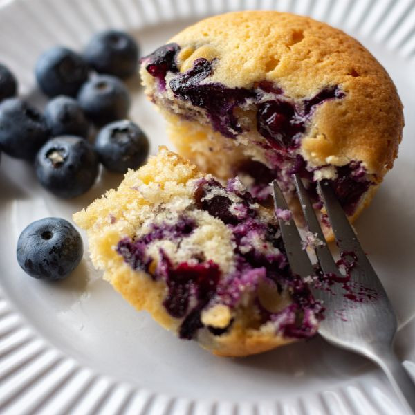 A white plate with a Wild Blueberry Muffin on it