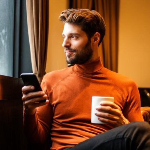 a man sitting on a couch holding a cup of coffee