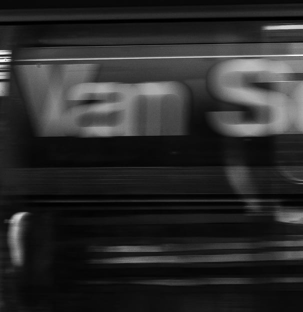 a blurred black and white image of the inside of a subway car while its whirring by the van siden
