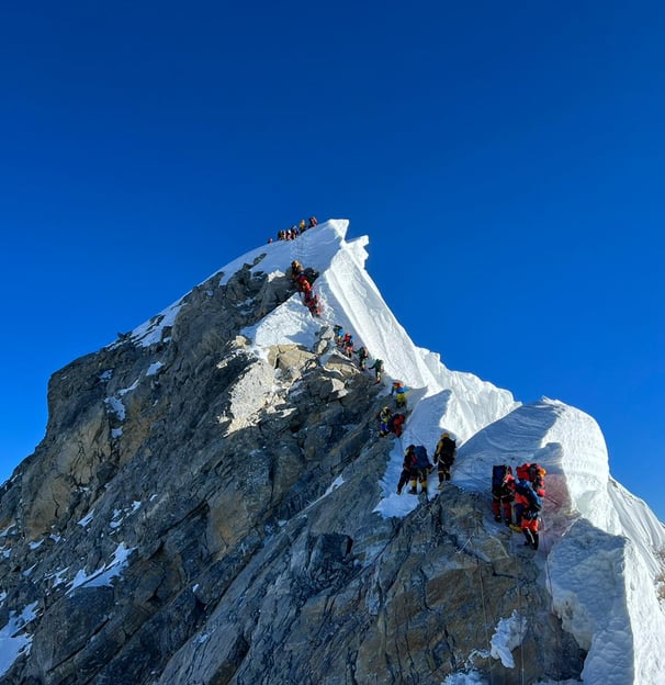 Climbers on snowy peak – Mountaineers ascending a snow-covered mountain ridge under a clear blue sky