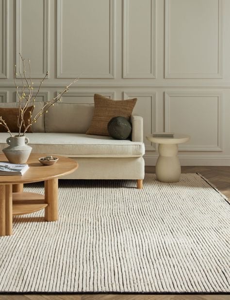 neutral living room with neutral coffee table, pillows and couch