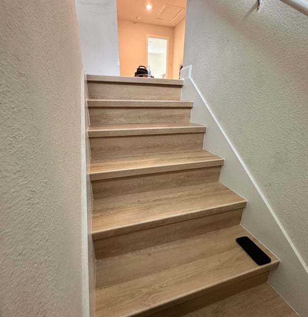 Modern staircase renovation with hardwood treads, black metal railings, and open risers in a Kissimm