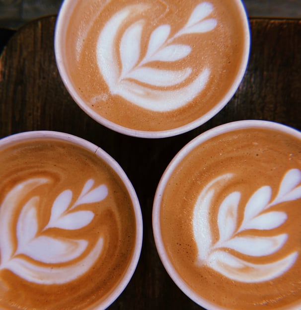three cups of coffee with a leaf design on the bottom