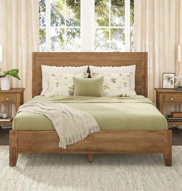 neutral bed frame with a green comforter with neutral side tables and cream linen curtains