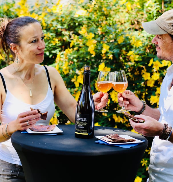 Couple en train de trinquer avec du cidre et manger des galettes à l'extérieur