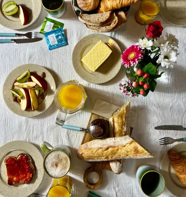 Brunch gourmand avec viennoiseries, fruits frais et fleurs, servi dans une location de charme