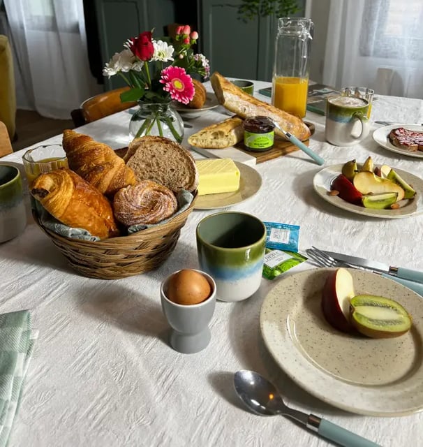 Petit-déjeuner gourmand avec viennoiseries, fruits frais et fleurs, servi dans une location de charme