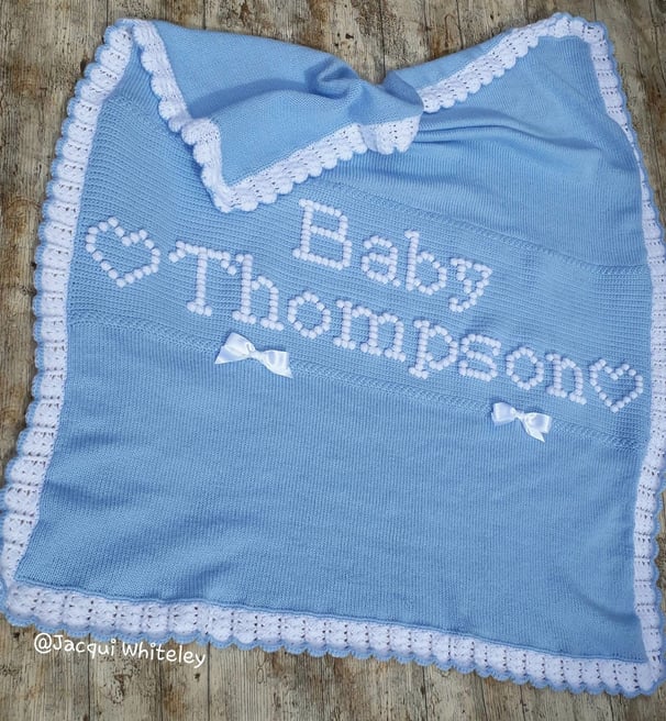 Custom made knitted and crochet baby blanket with raised lettering "Baby Thompson" and hearts.