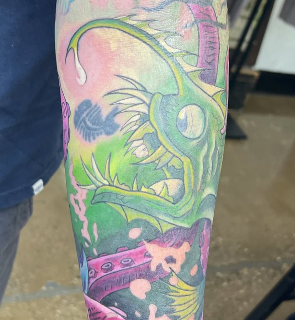 a man with a tattoo on his arm of a fish color tattoo