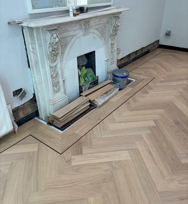 An oak herringbone floor with a double border and inlay