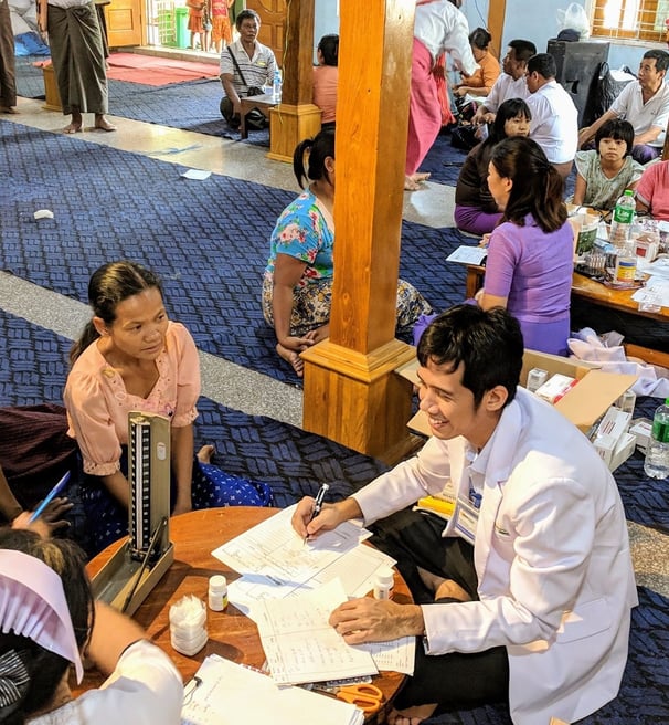 Doctor Zaw surrounded by patients sitting and counselling them in a smile