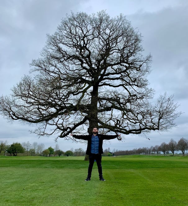 a man standing in front of a large tree