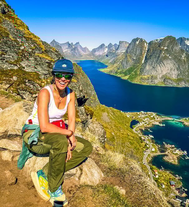 Hiker enjoying summer view from Reinebringen trail above Reine near Maritime Munchies in Lofoten