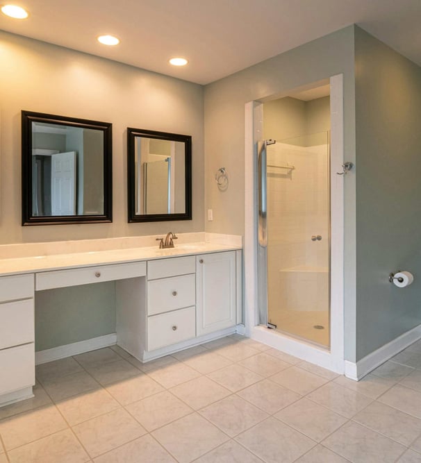 Image of basic bathroom with double vanity, framed mirrors, and enclosed shower