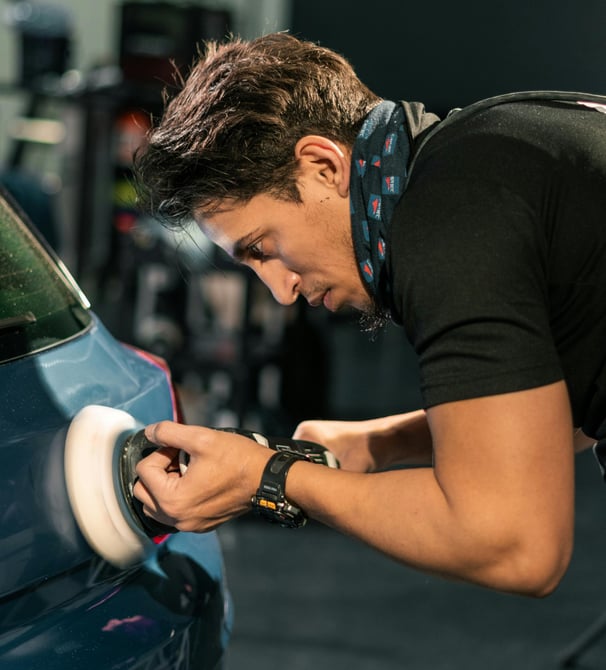 a man in a black shirt is polishing a car