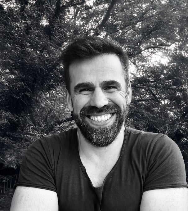 Adnan Erzen, Tai Ji and Qi Gong instructor at WDP Türkiye, smiling outdoors in a forest setting.