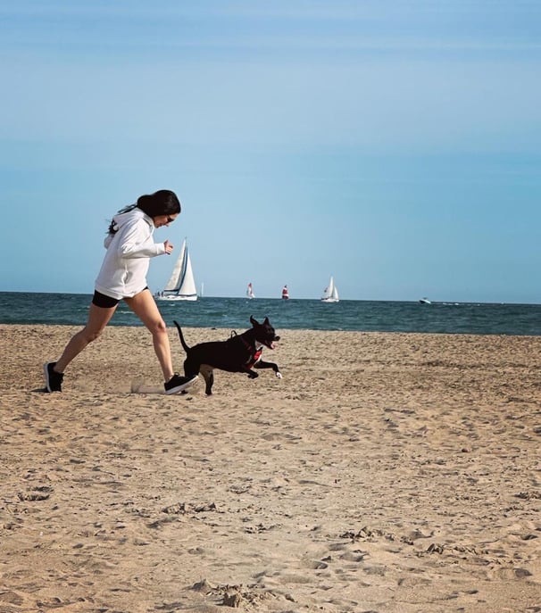 a woman running on the beach with a dog