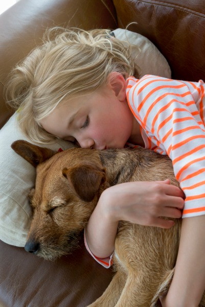 a young girl is sleeping on a couch with her dog