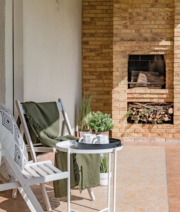 a patio with a table and chairs and a fireplace