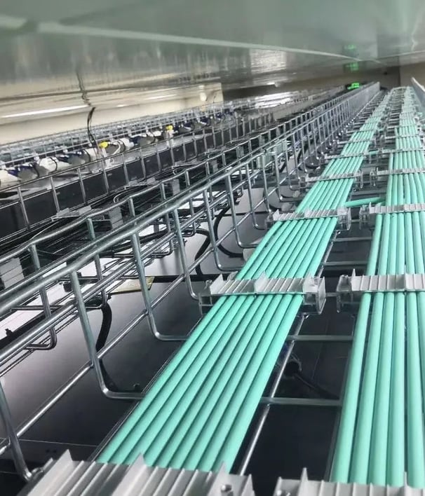 una bandeja de cables de malla de alambre con cables verdes y fijador de cables