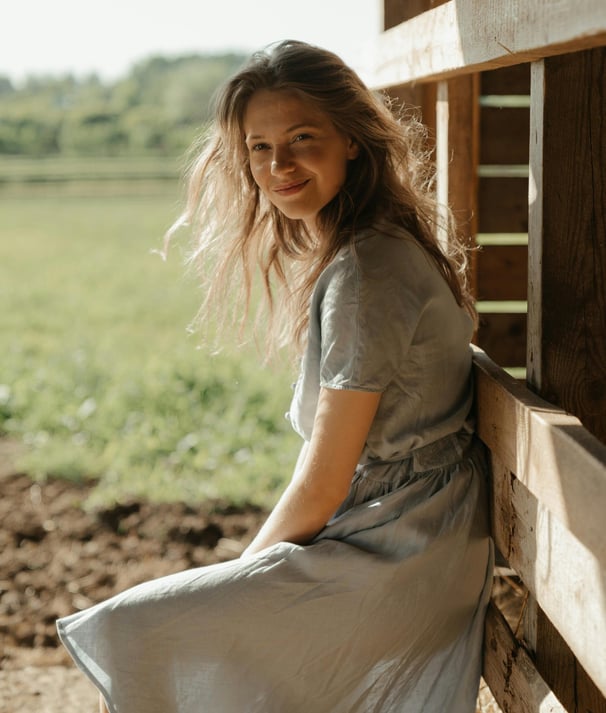 Young lady at a farm, wearing an eco-friendly dress, probably made of linen or hemp.