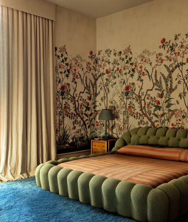 green bed frame with linen curtains and a blue rug