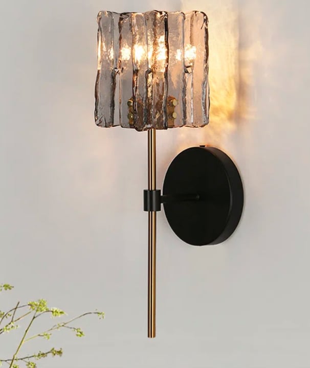 black and gold battery sconces on a neutral grey wall the light is moody and dark