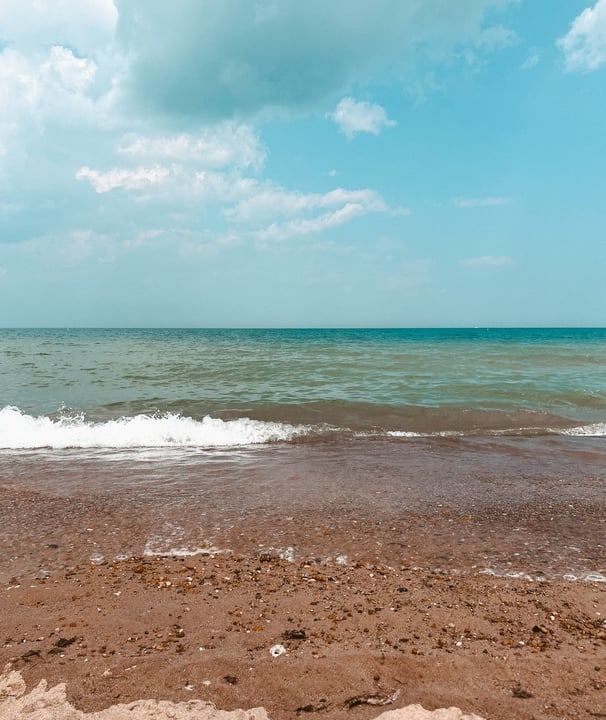 Serene Lake Michigan shoreline with calm waves, sandy beach, and blue skies, reflecting the tranquil essence of Lakeside Yin.