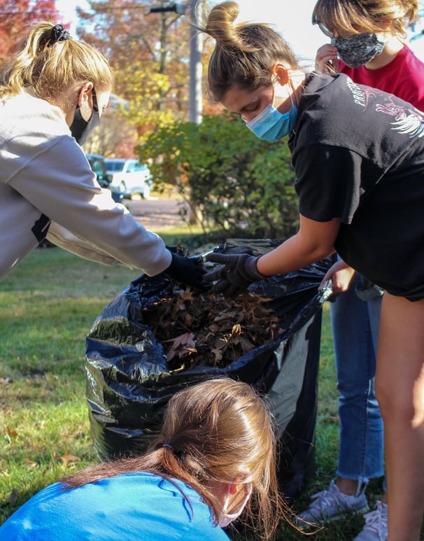 Group of young adult volunteers bagging leaves.