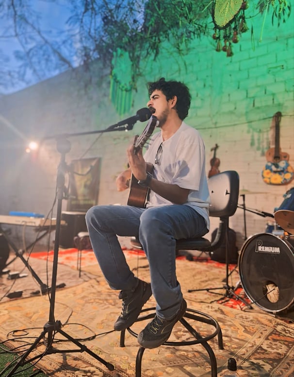 Augusto Moura tocando violão e cantando músicas de Raul Seixas e Legião Urbana no evento do Institut