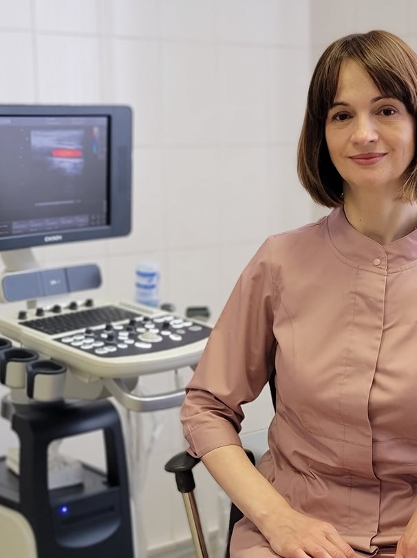 A doctor sits behind an ultrasound machine.