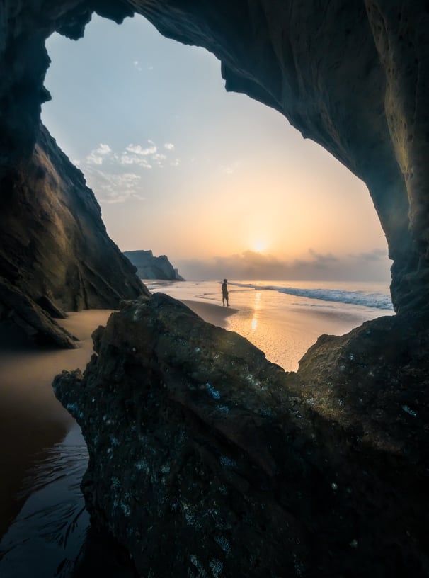 a person standing on a rock formation in the ocean .  arbab naimat kasi , balochistan , sapat