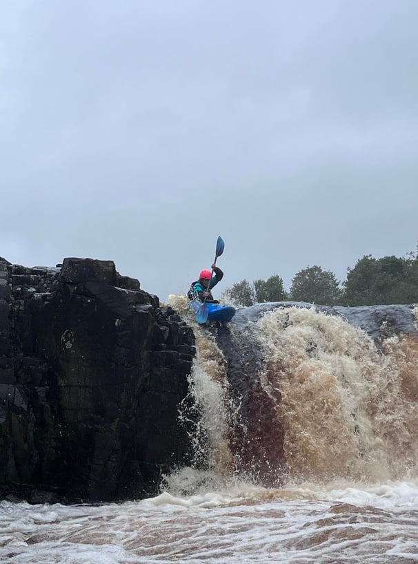 a women paddling a Pyranha Scorch off a waterfall (low force waterfall on the Tees) 