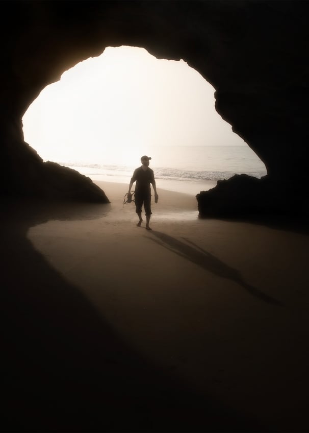 a man walking on the beach with a surfboard . arbab naimat kasi balochistan