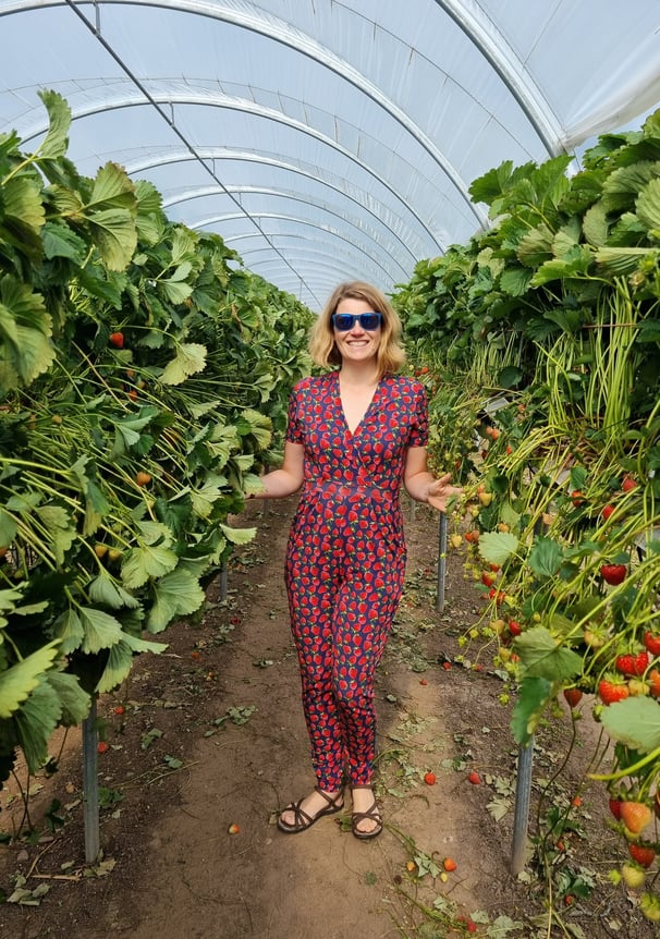 Designer and creator of clothing at Distinctly Individual woman in strawberry print jumpsuiti