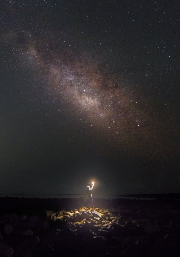 a person standing on a rocky beach with a flashlight