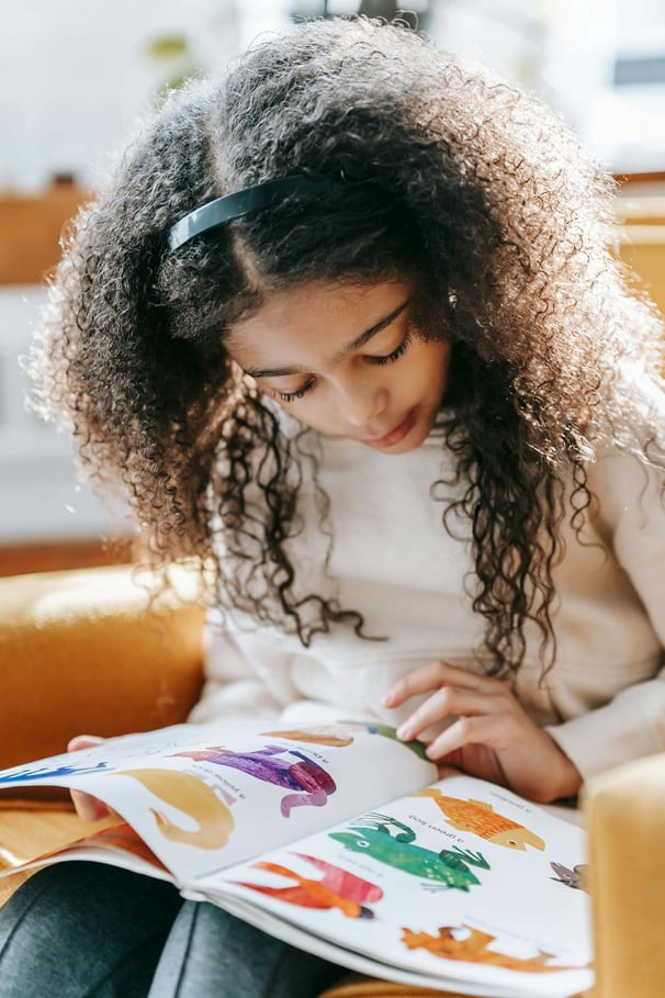 A young girl reading a children's picture book.