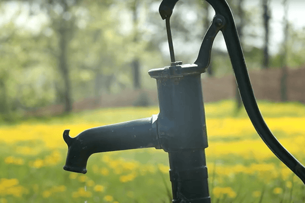 Image of a brass well faucet in a meadow