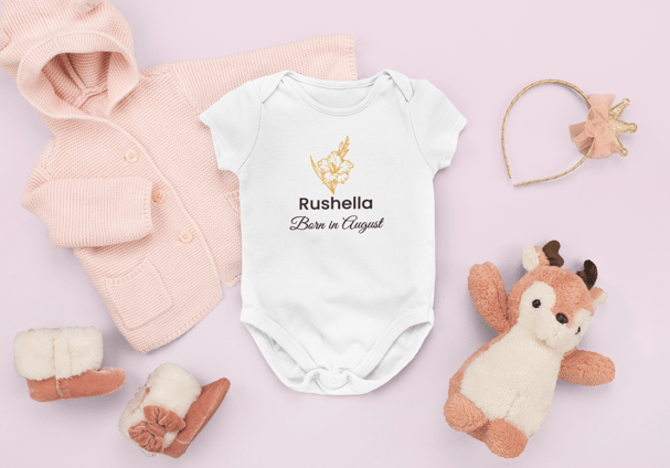 Flat lay of a personalised white baby grow with a red rose and 'Born in June' text, surrounded by so