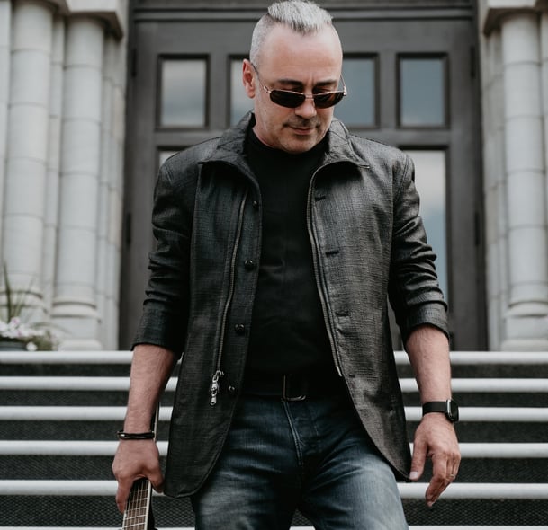 a man in a leather jacket and sunglasses holding a guitar