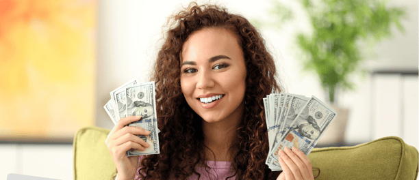 a woman sitting on a couch holding a laptop and holding money