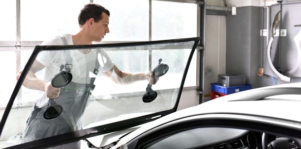 worker lifts windshield onto car frame