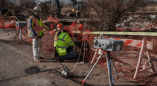 a man in a yellow vest and a camera on a tripod