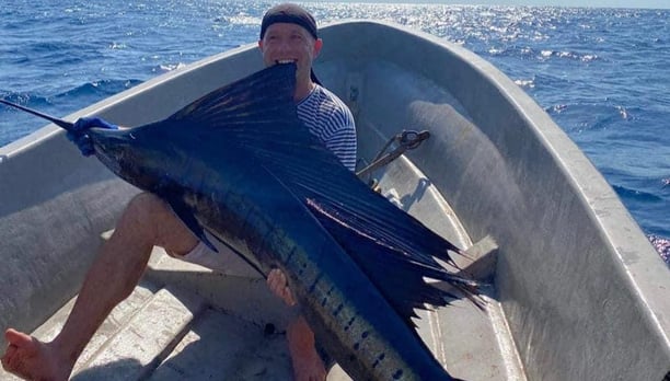 Fisherman with an impressive sailfish caught during a deep-sea fishing charter in Zanzibar