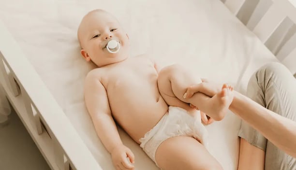 Una persona ayudando a un bebe con ejercicios de fisioterapia para displasia de cadera